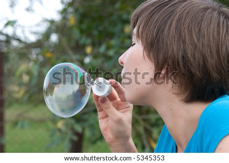 young woman blowing soap bubbles, close up