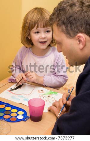 little, cute girl painting with father\'s helping hand