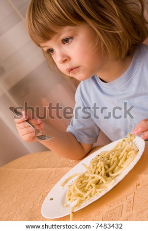 little cute girl eating spaghetti with pesto sauce