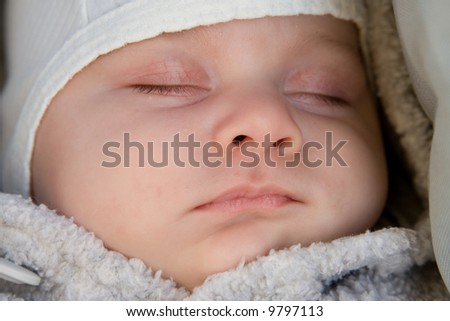 little baby boy in cap sleeping calmly outdoors