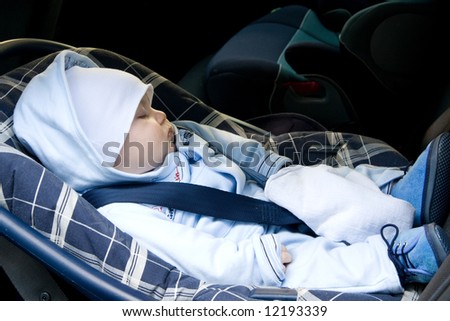 little baby boy sleeping in safety car seat