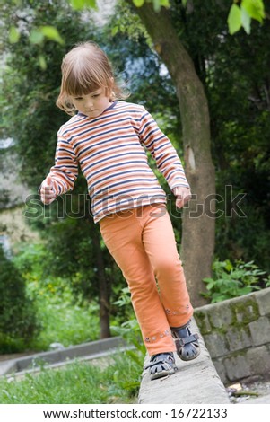 little girl walking on narrow path and trying to keep balance