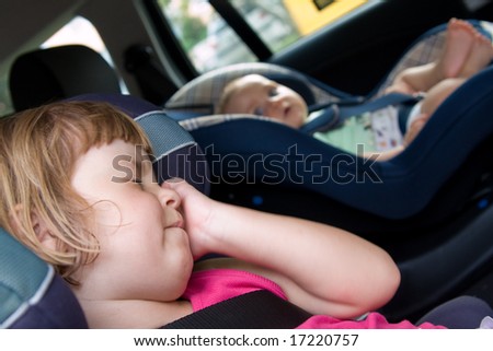 little baby and girl sitting in safety car seat