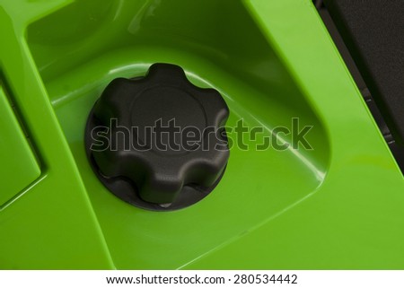 A new round black plastic petrol cap fitted to an all-terrain vehicle with shiny automotive lime green paint
