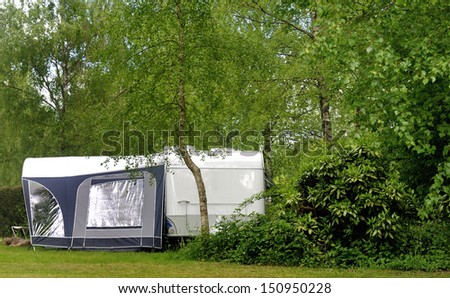 Campside with caravan and a small forest