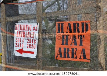 Hard hat area sign post on a fence outside a construction zone.