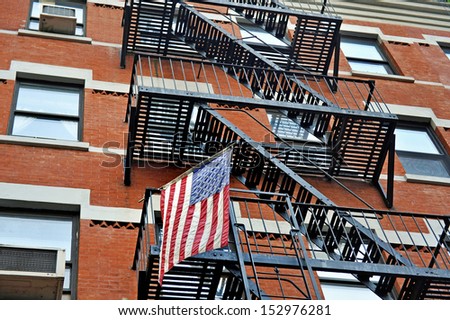 Fire escape stairs outside a New York apartment building with the American national flag