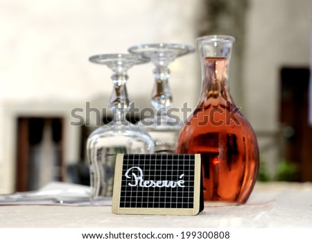 Reserved sign at a restaurant table in France.With glasses and a decanter filled with rose wine