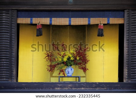 Vase with flowers against yellow background in the Imperial Palace, Kyoto, Japan