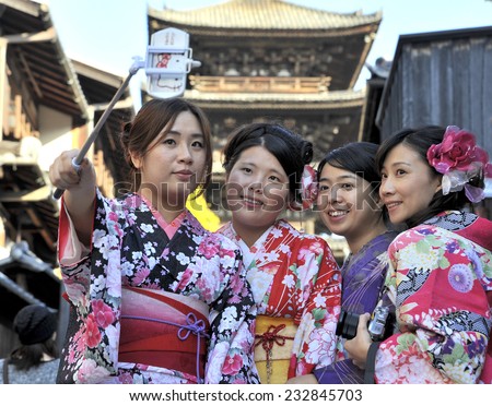 KYOTO,JAPAN - NOVEMBER 4: Geisha women in traditional dress making a selfie with a telephone in front of the Yasaka-no-To Pagoda. November 4, 2014 Kyoto, Japan.