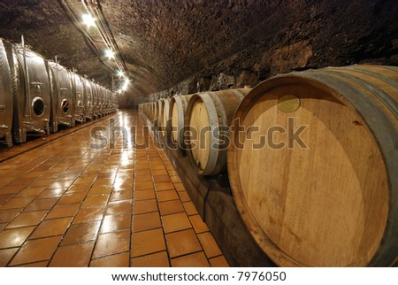 Modern metal and old fashioned wooden wine barrels in a cave