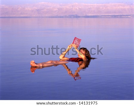 Girl floating at the Dead Sea, Jordan while reading a book