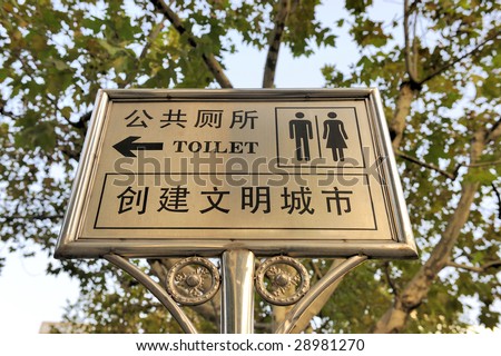 Sign, in Chinese and English in black letters and characters, indicating the way to the public rest rooms