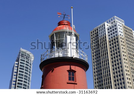 Lighthouse between two sky scrapers against clear blue sky
