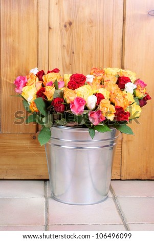 bunch of roses in tinny bucket on a wooden background