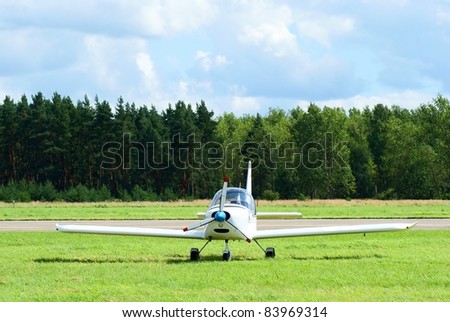 Small sports airplane parking on grass - front view