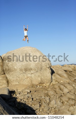 A woman jumps for joy when she reaches the top of the hill