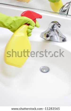 A person cleaning the bathroom sink with a glove