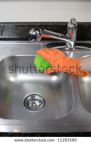 A person cleaning the kitchen sink with a glove