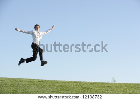 A business man jumping for joy on a hill