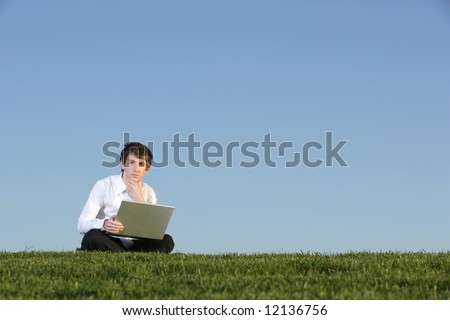 A business man out of the office in a field on a laptop