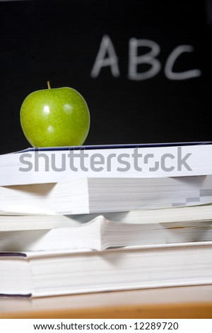 An apple on a stack of books on the teachers desk