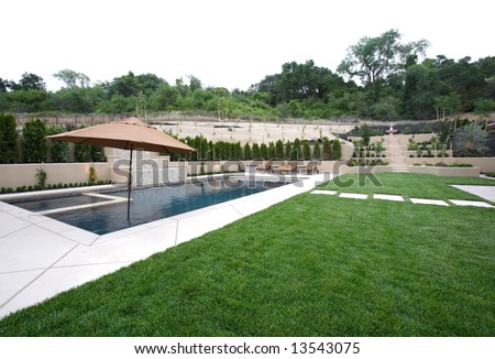 A pool with a waterfall in a luxury backyard with new landscaping