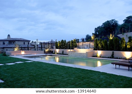 A pool with a waterfall in a luxury backyard with new landscaping