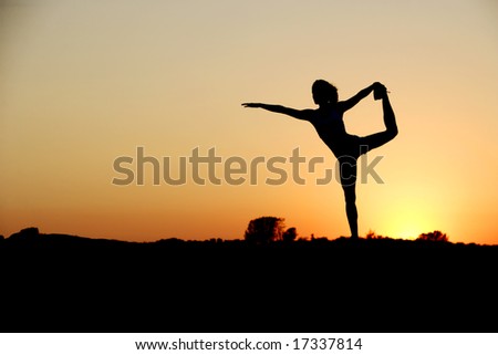A young woman on top of a rock going yoga at sunset in a white fitness outfit