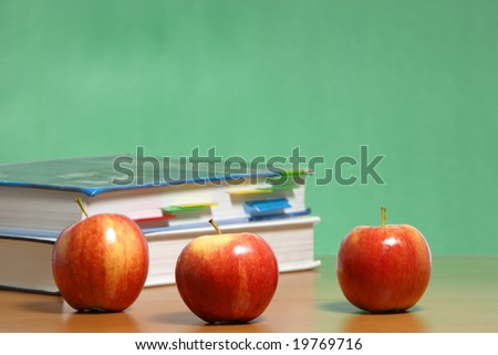 An apple on a stack of books on the teachers desk