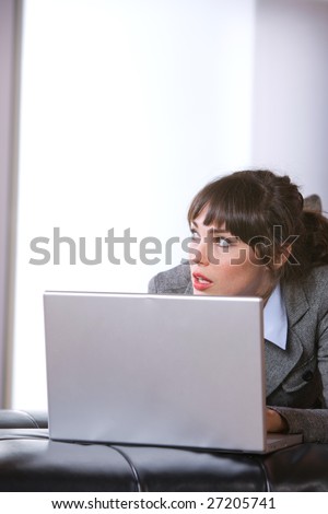 Business woman thinking in modern office with laptop