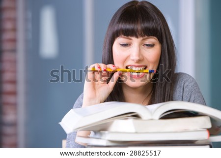 Young student studying biting the end of a pencil