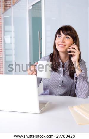 Business Woman on a cell phone and laptop in modern office