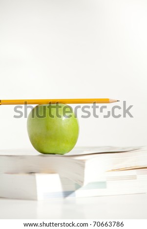 A Pencil on top of an Apple and books