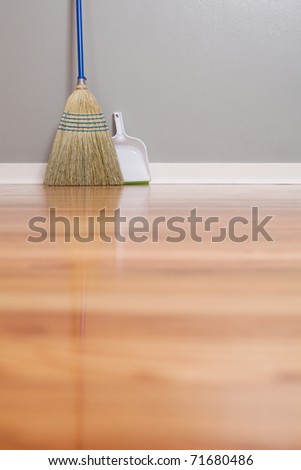 A Corn Broom on New Hardwood Flooring with a dust pan