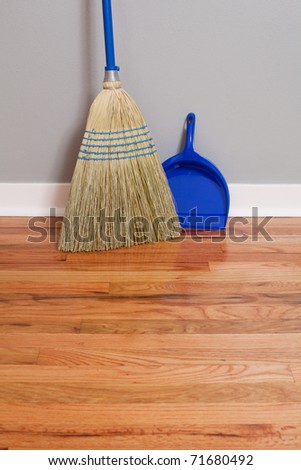 A Corn Broom on New Hardwood Flooring with a dust pan