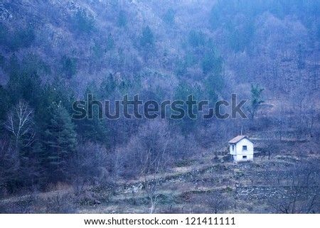 Old rough log cabin on a hill with trees with their fall dress