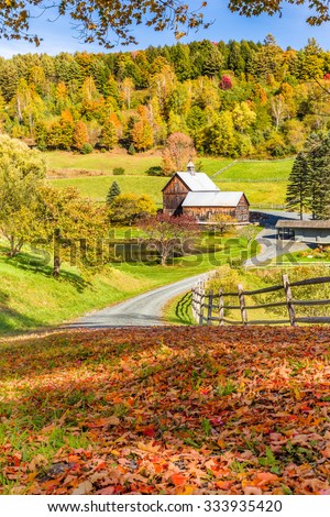 Wooden barn in fall foliage landscape in Vermont countryside.