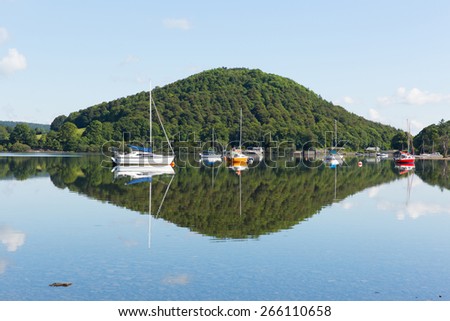 Calm peaceful relaxed morning on a still day at a beautiful lake with cloud reflections from a hill and sailing boats