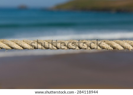 Length of rope pulled tight against a blurred background of sea waves and coast