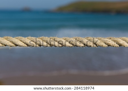 Length of rope pulled tight against a blurred background of sea and coast