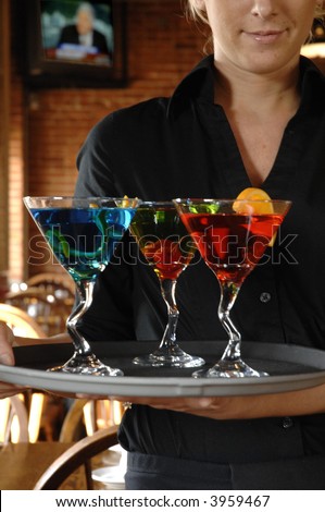 3 colorful drinks on a serving tray with waitress