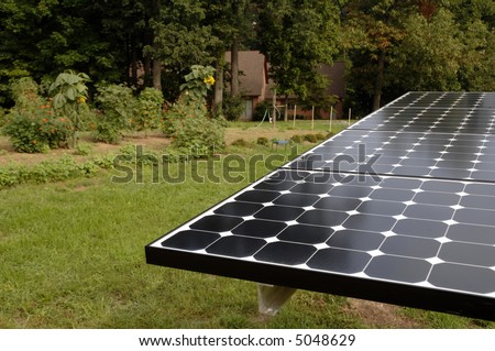 a solar panel with a home and garden behind