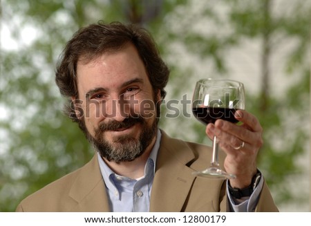 a man lifts a glass of red wine in celebration