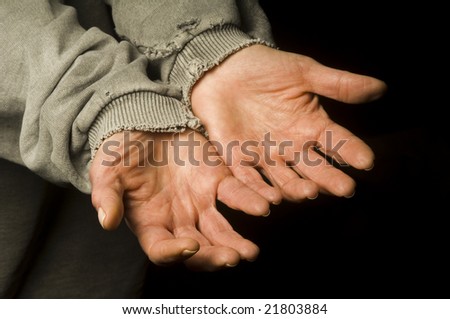 the hands of a beggar in an old shirt