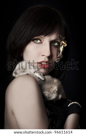 Glamorous young woman holding the little rabbit on her shoulder/Living fur