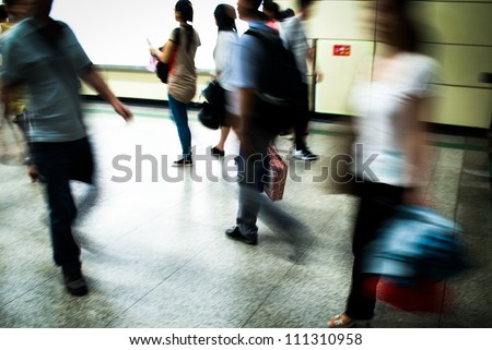 Busy city people walking in subway station in motion blur