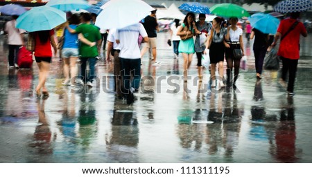 Busy city people walking in rain in motion blur