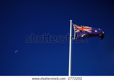 waving australian flag on a post, blue sky, moon