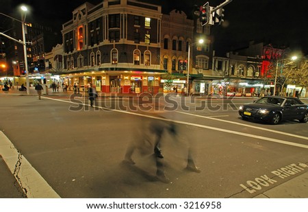night scene in Sydney - Taylor Square; pedestrians crossing a street are blurred